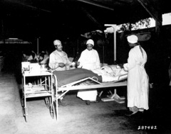 Three nurses attend to a patient in bed.