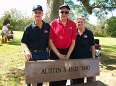 Three people standing behind granite bench engraved with "Austin's Old 300"