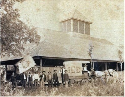 Historic photo of people standing in front of brewery with banner waving.