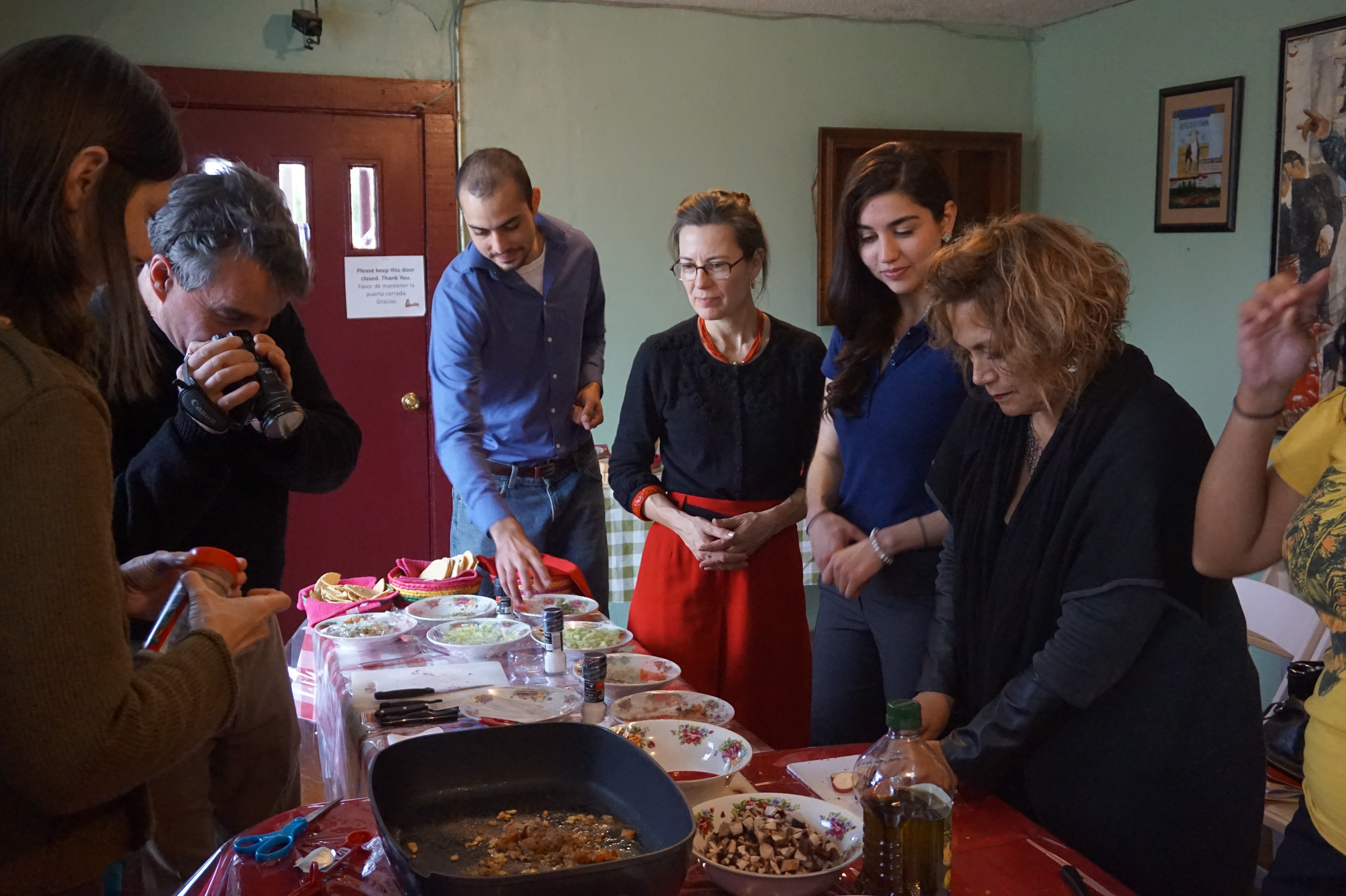 Participants standing around a table of Mexican food during a cooking class in Laredo. 