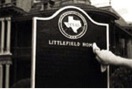 A hand wipes black lacquer off the type and logo on a historical marker in the process of restoration