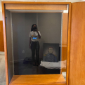 Reflection of a young woman in the glass of a tall wooden museum exhibit case