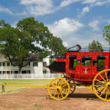A stagecoach sits in front of a white house