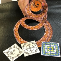 colorful spiral snake cut from paper behind Mexican printed talavera tile magnets