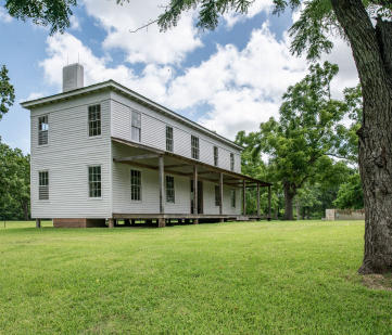 Side view of the main white plantation house surrounded by green grass and trees