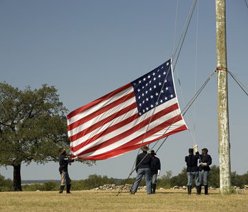 Reenactors raise the US flag.