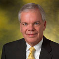 A man in a yellow tie and dark suit.