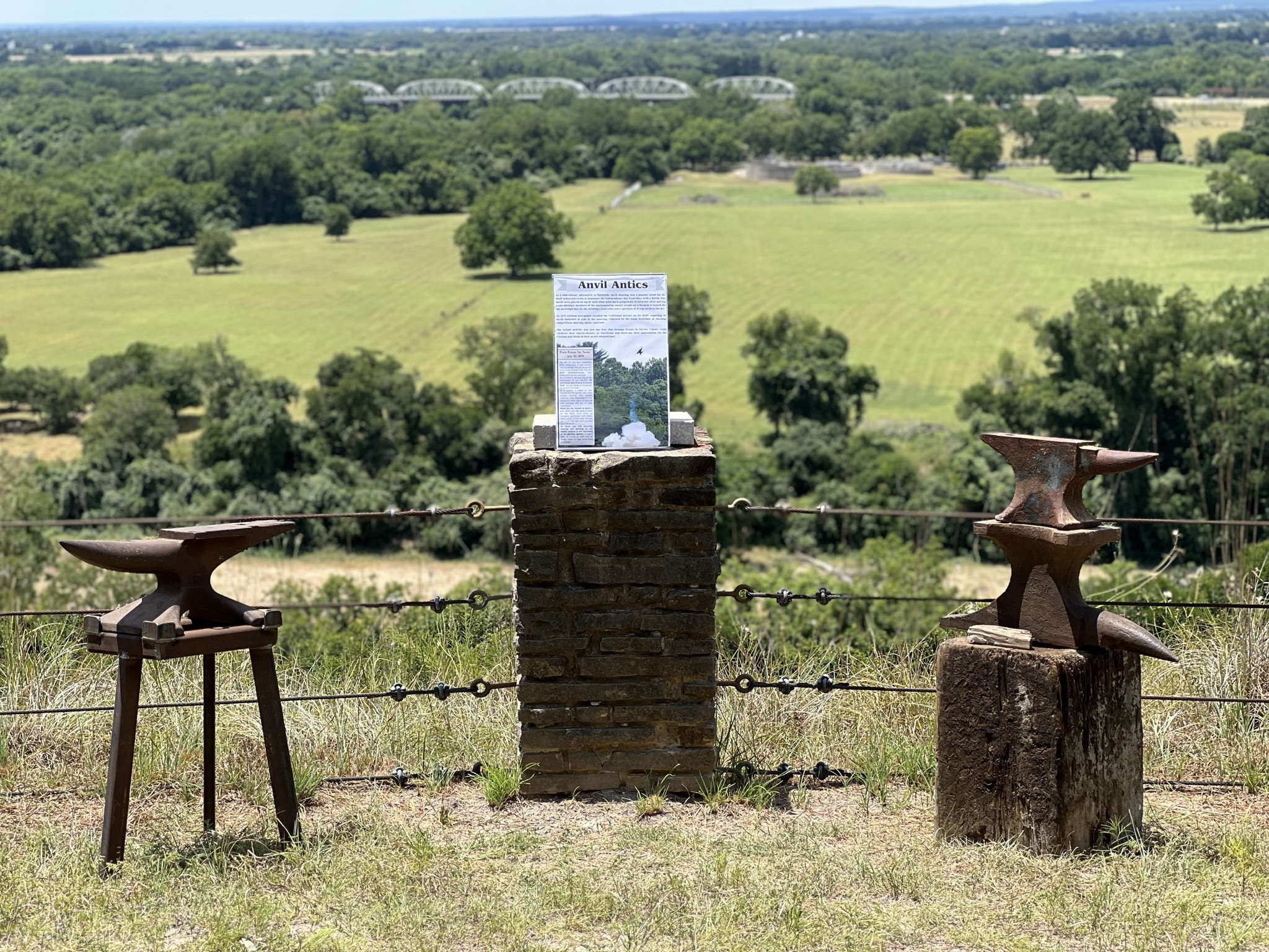 Two anvils on stands with an interpretive sign in the middle
