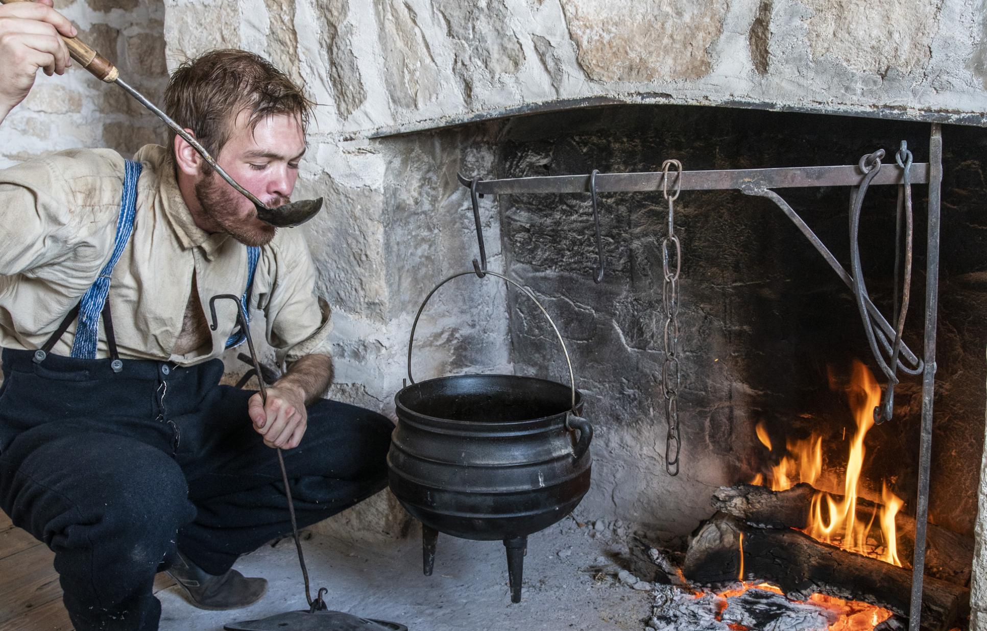 Site educator demonstrating cooking on an open hearth