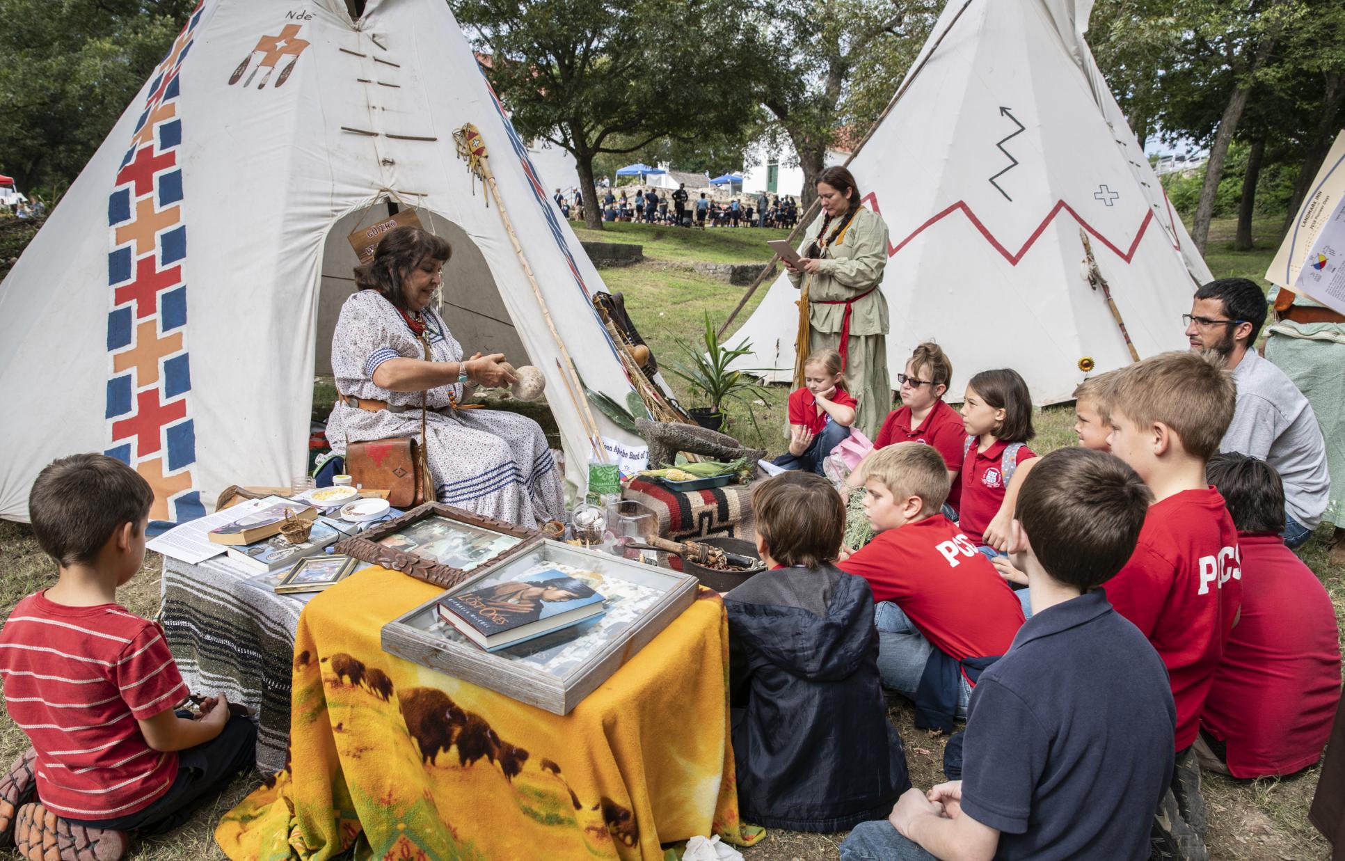 Native American reenactor talking to children during a living history event