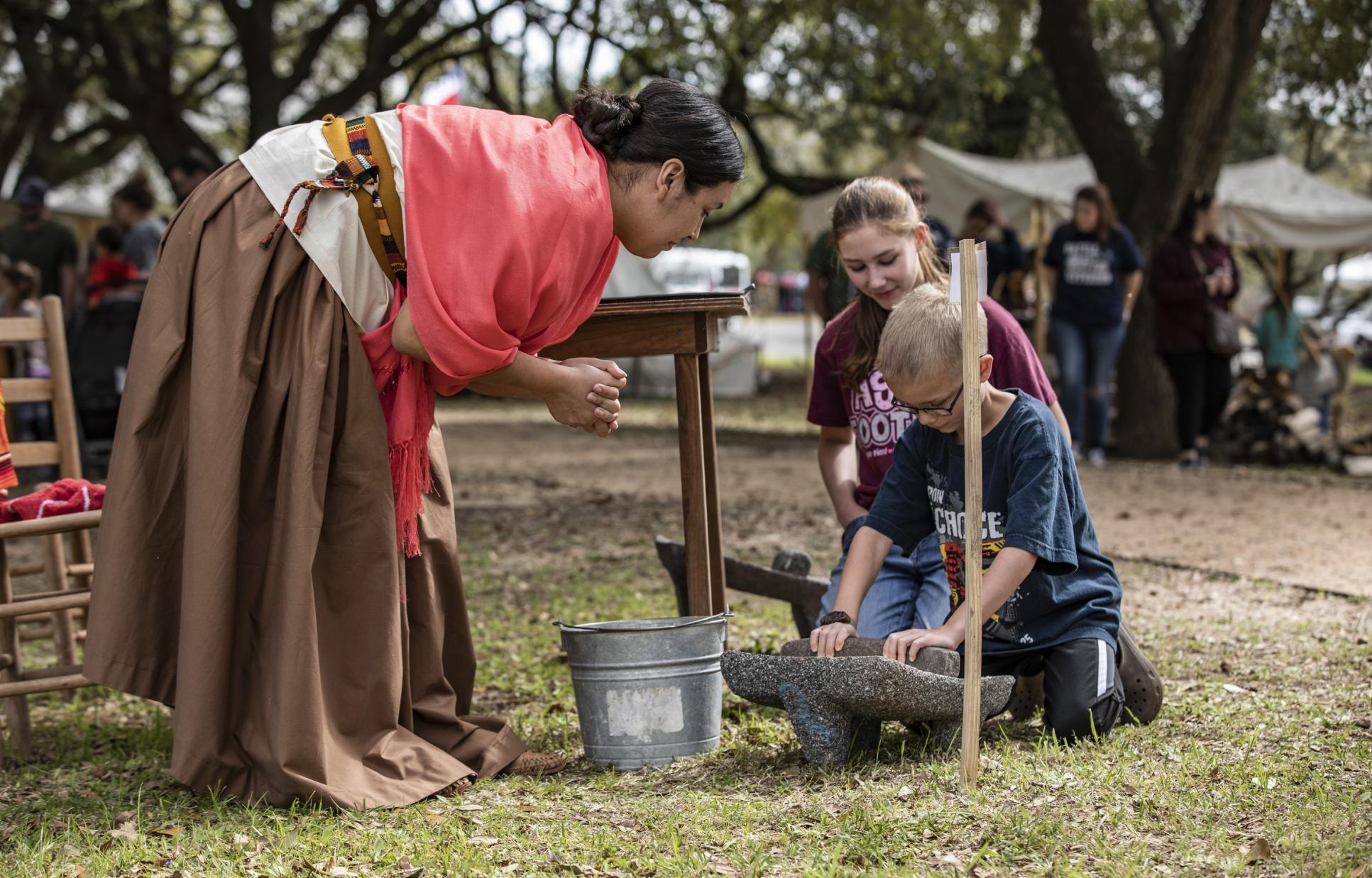 Reenactor demonstrating food preparation to children at Washington on the Brazos 
